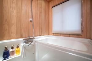 a bathroom with a white tub and a white sink at Rinn Gion Kenninji in Kyoto