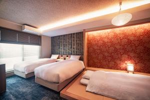 two beds in a room with red wallpaper at Rinn Gion Kenninji in Kyoto