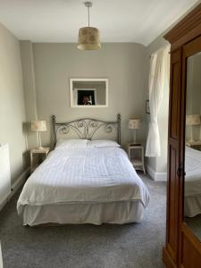 um quarto com uma cama com um edredão branco e um espelho em The Penrhos Arms Hotel em Llanfairpwllgwyngyll
