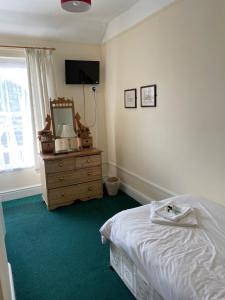 ein Schlafzimmer mit einem Bett und eine Kommode mit einem Spiegel in der Unterkunft The Penrhos Arms Hotel in Llanfairpwllgwyngyll