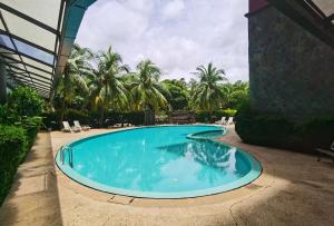 einen Pool in einem Garten mit Palmen in der Unterkunft Luï Luï Comfy Condo in Great Location in Kuah