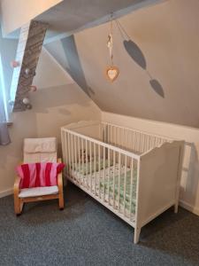 a baby room with a crib and a chair at Haus Steindöbra in Klingenthal