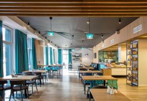 a restaurant with tables and chairs and windows at MEDEA Apartments by UPA in Druskininkai