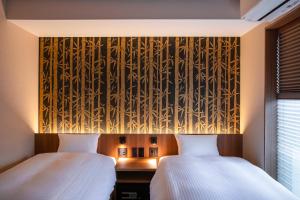 two beds in a room with a wall with bamboo at Rinn Gion Kenninji in Kyoto