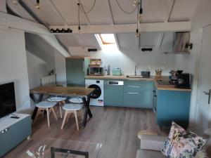 a kitchen with blue cabinets and a table and chairs at LE CHALET DES THERMES in Nancy +3 photos