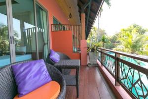 a balcony with a chair and purple pillows at Mai Morn Resort SHA Plus in Phuket Town