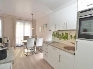 a kitchen with white cabinets and a table with chairs at Wohnpark Stadt Hamburg - Apt. 09 in Binz