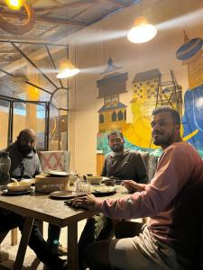 a group of men sitting at a table at ThePahadians Food & Stay in Jibhi