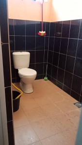 een badkamer met een toilet en een zwart betegelde muur bij Sobey Laris Homestay D’ZIY AD in Merapuh