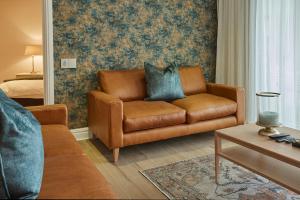 sala de estar con sofá de cuero marrón y cama en African Elite Waterfront en Ciudad del Cabo