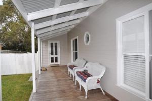 a porch with four wicker chairs on a house at Paperbark Homestead Pet Friendly in Inverloch