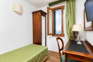 a room with a bed and a desk and a window at Hotel Giardinetto Venezia in Venice-Lido