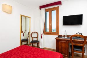 a bedroom with a bed and a desk and a television at Hotel Giardinetto Venezia in Venice-Lido