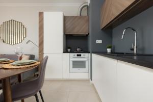 a kitchen with white cabinets and a wooden table at Lakeview Apartment Kapelanów Armii Krajowej by Renters in Warsaw