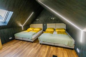 2 Betten mit gelben Kissen in einem Schlafzimmer im Dachgeschoss in der Unterkunft Natura Park Radawa in Radawa