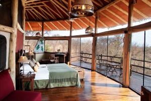 a bedroom with a bed in a room with windows at Tarangire Treetops in Kwa Kuchinia