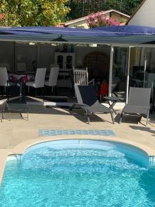 a swimming pool with chairs and an umbrella at LA MAISON DES HIPPOCAMPES in La Teste-de-Buch