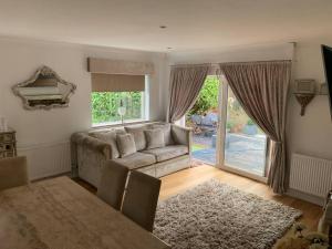 a living room with a couch and a table at Wychwood A Beautiful Country Style Bungalow in Ash