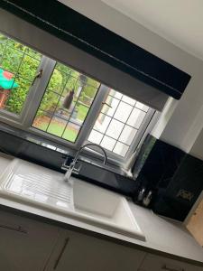 a kitchen with a sink and a window above it at Wychwood A Beautiful Country Style Bungalow in Ash