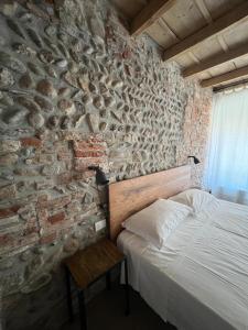 a bedroom with a stone wall with a bed and a table at Borgovivobg il tuo rifugio in centro città in Bergamo