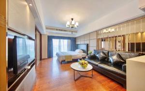 Foshan Yumi Apartment Bodun Branch في فوشان: غرفة معيشة بها أريكة وسرير وتلفزيون