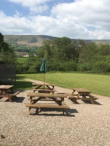 eine Gruppe Picknicktische mit einem Sonnenschirm in der Unterkunft luxury railway carriage with stunning views in Hereford