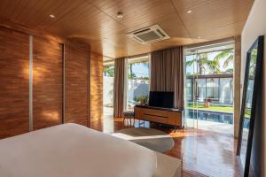 a bedroom with a bed and a tv and some windows at One Eleven in Seminyak