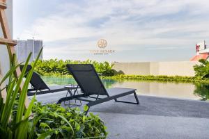 two chairs and a table next to a body of water at UNA Serviced Apartment, Sunway Velocity Kuala Lumpur in Kuala Lumpur