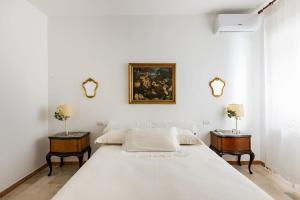 a white bedroom with a large bed and two tables at B&B Casa Sabella in Lecce