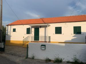 een wit huis met een groene deur en een balkon bij Casa Agostinho - with private pool near Coimbra 