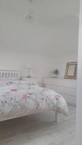 a white bedroom with a bed with a floral comforter at Amberley in Gorey