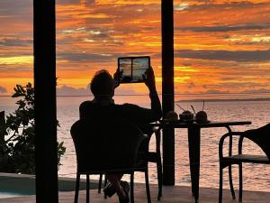 a person sitting at a table taking a picture of the sunset at South Pacific Memories in Port Vila