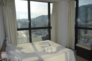 Cama blanca en habitación con ventana grande en Apart Riviera Tower Suites en Villa Carlos Paz