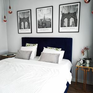 a bedroom with a large white bed with four pictures on the wall at Woronicza Premium in Warsaw