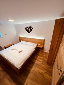 a bedroom with a bed with white sheets and a heart on the wall at PJagodic Hotel Cerklje - 5min to Airport in Cerklje na Gorenjskem
