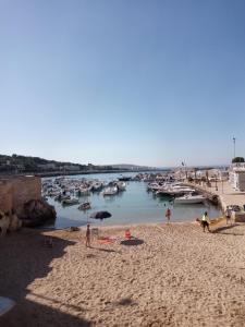 un gruppo di persone su una spiaggia con barche in acqua di Kamares a Nardò