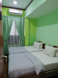 twee bedden in een kamer met groene muren en een raam bij 1511 Guest House in Melaka