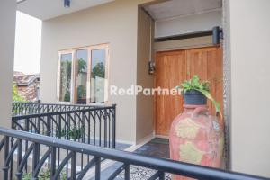 a balcony with a wooden door and a vase with a plant at Rumah CIA Taman Siswa near Malioboro Yogyakarta Mitra RedDoorz in Timuran