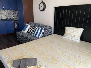 1 dormitorio con cama, sofá y reloj en Apartment Perfect en Pomorie