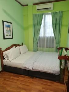 a bedroom with a bed and a window with curtains at 1511 Guest House in Melaka