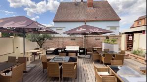 un patio al aire libre con mesas, sillas y sombrillas en Boutique Hotel Golf Garni, en Mikulov