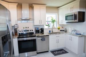 a kitchen with white cabinets and a stove top oven at Light & Cozy House in Pompano Beach - BBQ, Patio, Parking in Pompano Beach +7 photos