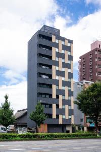 a tall gray building in a city at Rinn Horikawa Gojo in Kyoto