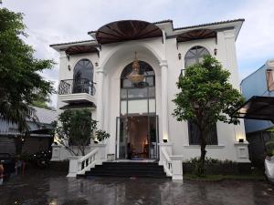 a white house with a staircase in the rain at Hotel My Cang in Trà Vinh