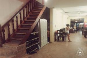 a woman standing next to a staircase with wine bottles at Tony Central Hostel in Luang Prabang