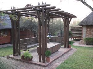 a wooden pergola with a bench in a yard at Monkey Thorn in Roodeplaat