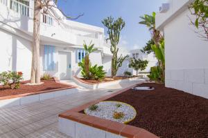 a courtyard of a white building with trees and plants at Checkin Bungalows Atlántida in Los Cristianos