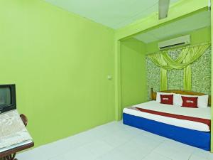 a bedroom with a bed with a window and a television at OYO 90454 Haza Harmoni Guesthouse in Kota Bharu