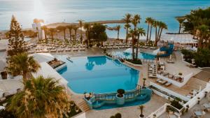 a beach with a pool, chairs, and a pool table at Golden Coast Beach Hotel in Protaras