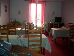 une salle à manger avec deux tables et des chaises ainsi qu'une fenêtre dans l'établissement Hotel L'Aiglon, à Limoges